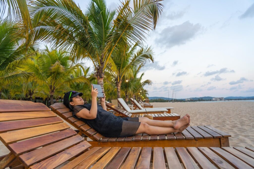 Young woman lying down palm tree against sky 1048944 27471584